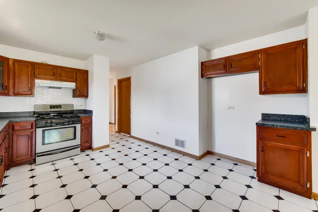 a kitchen with granite countertop a stove a sink and a refrigerator