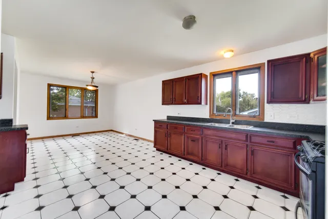 a kitchen with a sink a stove a window and cabinets