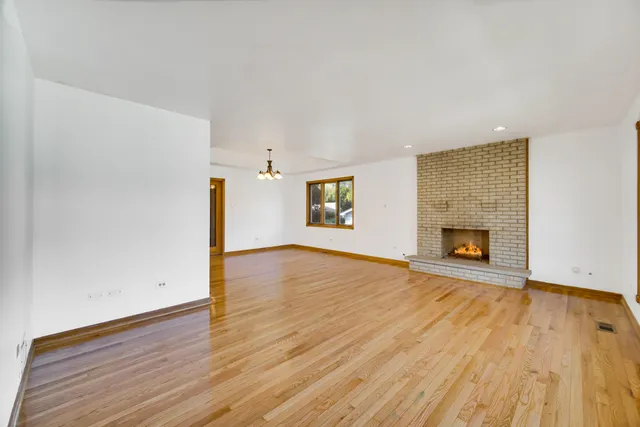 a view of empty room with wooden floor and fireplace