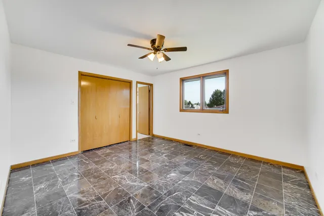 an empty room with windows and ceiling fan