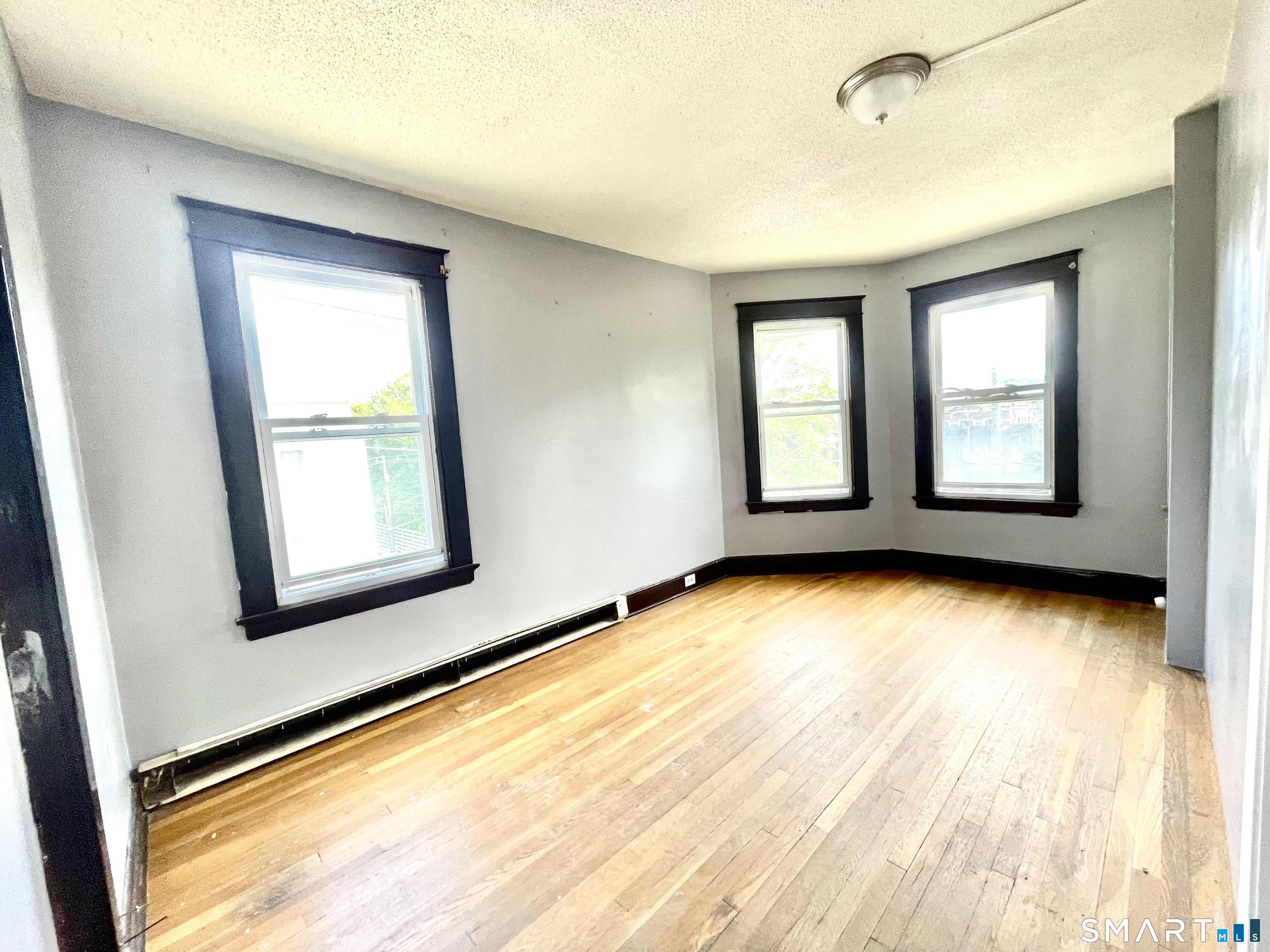 146 Charles Street, Unit 3 Waterbury, CT 06708 - Photo 18 of 20 a view of an empty room with a window and wooden floor