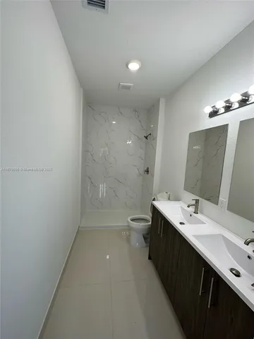 a bathroom with a double vanity sink toilet and shower