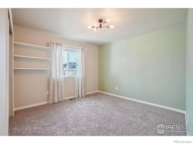 an empty room with closet and windows