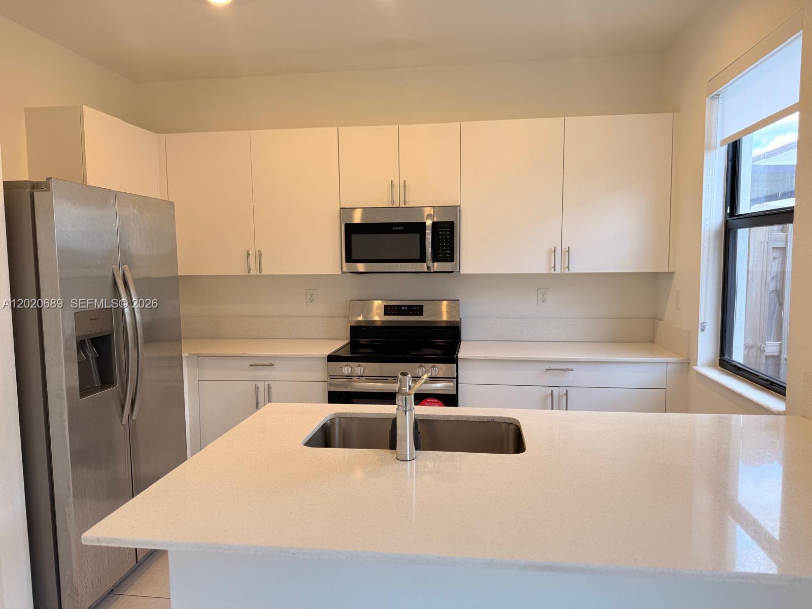 12875 Southwest 231st Terrace Miami, FL 33170 - Photo 10 of 25 a kitchen with kitchen island a refrigerator stove and microwave