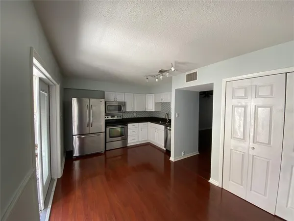 a view of kitchen with refrigerator and wooden floor