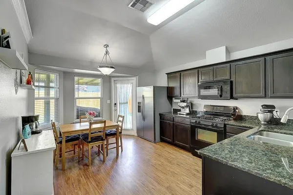 a kitchen with stainless steel appliances granite countertop sink stove refrigerator dining table and chairs