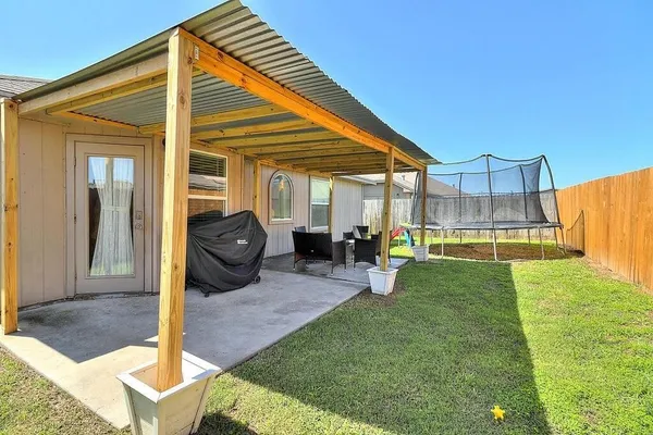 a view of a backyard with table and chairs and a barbeque