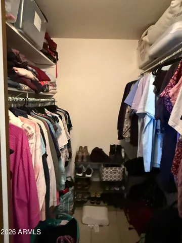 a view of walk in closet with clothes and shoes