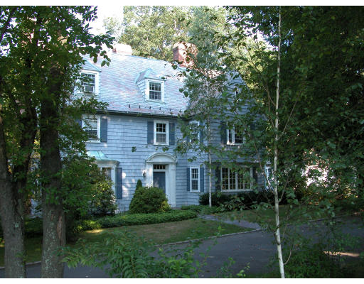 a view of a brick house next to a yard with big trees