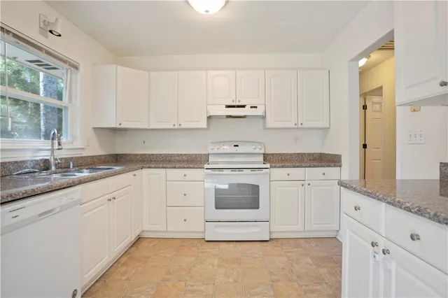 a kitchen with granite countertop white cabinets white stainless steel appliances with a sink and dishwasher