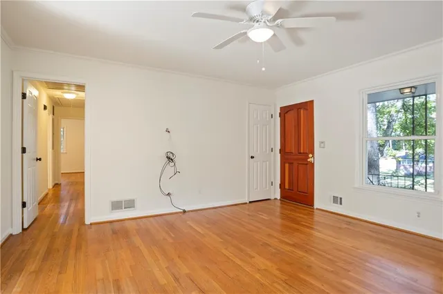 a view of an empty room with wooden floor and window