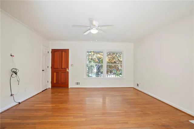 an empty room with wooden floor chandelier fan and windows