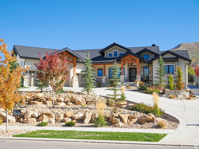 View of front of home featuring stone siding, a porch, and driveway