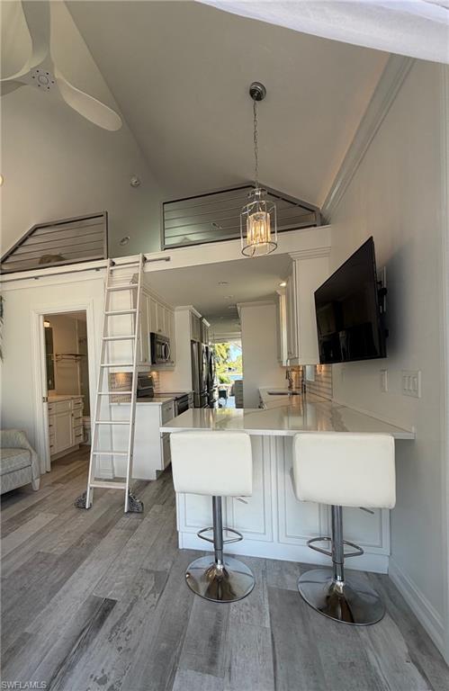4565 Southern Breeze Drive Naples, FL 34114 - Photo 12 of 19 Kitchen with a breakfast bar area, white cabinets, a peninsula, light wood-style floors, and stainless steel appliances