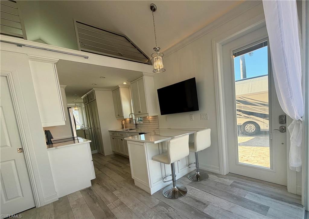 4565 Southern Breeze Drive Naples, FL 34114 - Photo 14 of 19 Kitchen with a breakfast bar, a peninsula, healthy amount of natural light, decorative light fixtures, and ornamental molding