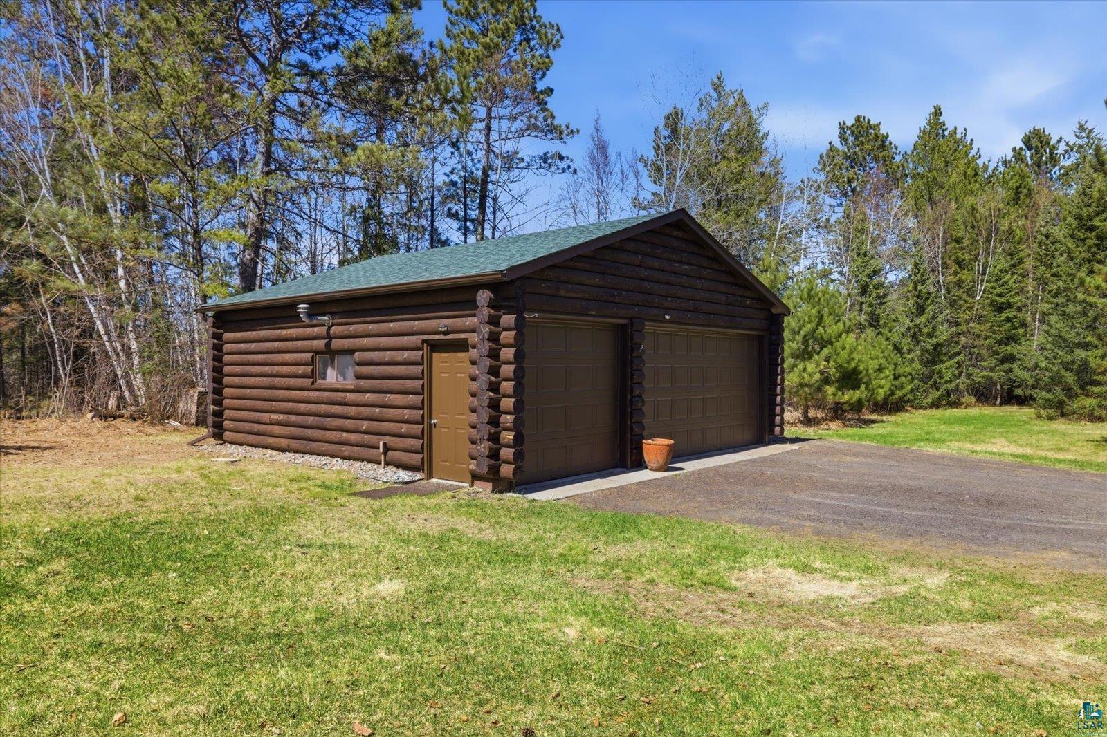 7185 Giants Ridge Road Embarrass, MN 55732 - Photo 34 of 47 Log-sided detached garage featuring two vehicle bays, a side entry door, and a green shingle roof