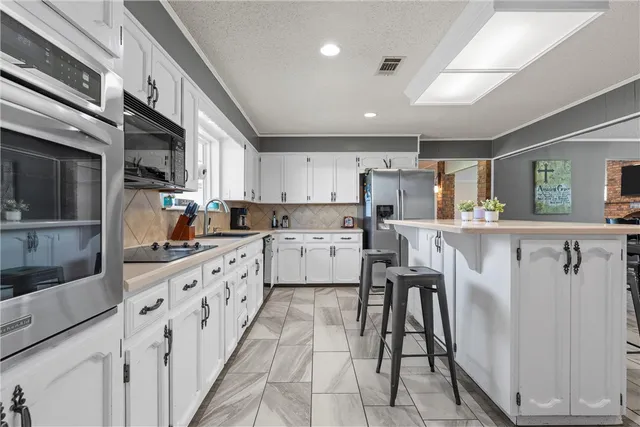 a kitchen with granite countertop white cabinets sink and stainless steel appliances