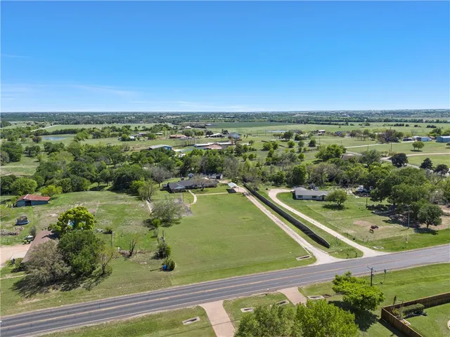 an aerial view of residential houses with outdoor space and trees