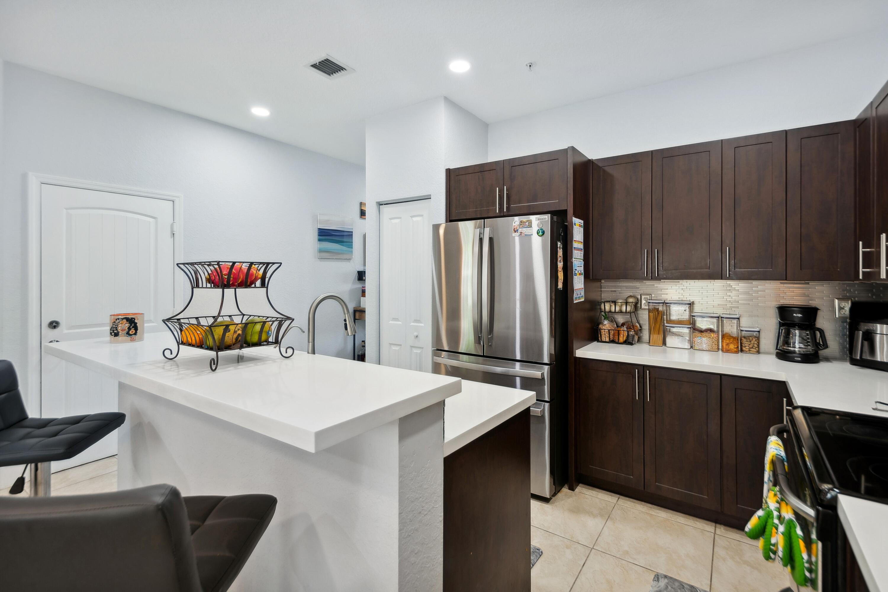 148 Southwest 7th Court Pompano Beach, FL 33060 - Photo 5 of 19 a kitchen with stainless steel appliances a refrigerator sink and wooden cabinets