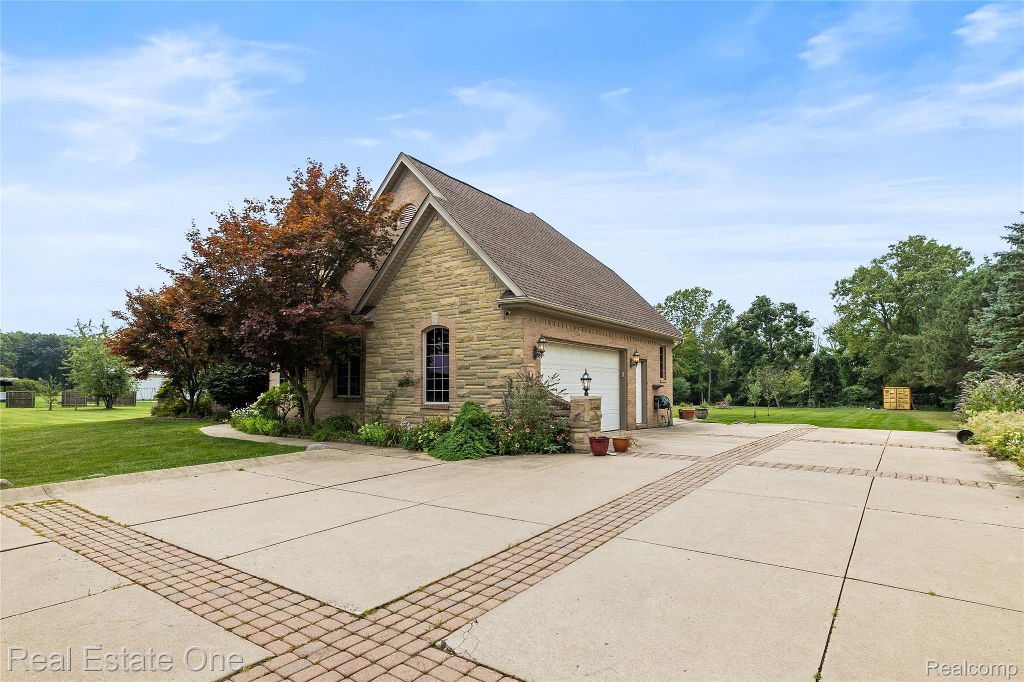 17268 Beech Daly Road Romulus, MI 48174 - Photo 16 of 60 Stone exterior with a gabled roofline, featuring a two-car garage with an automatic door