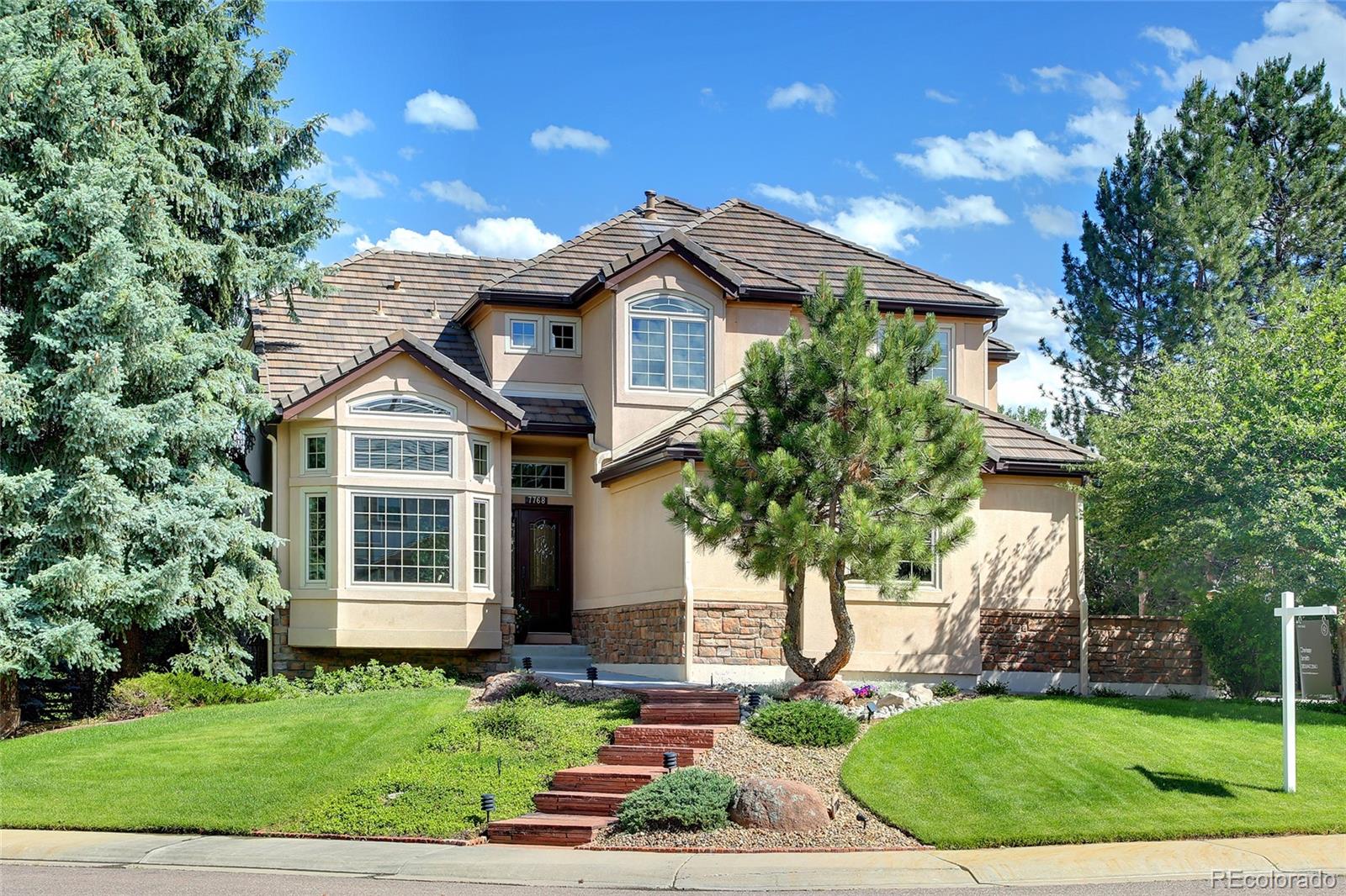 a front view of a house with a yard and potted plants