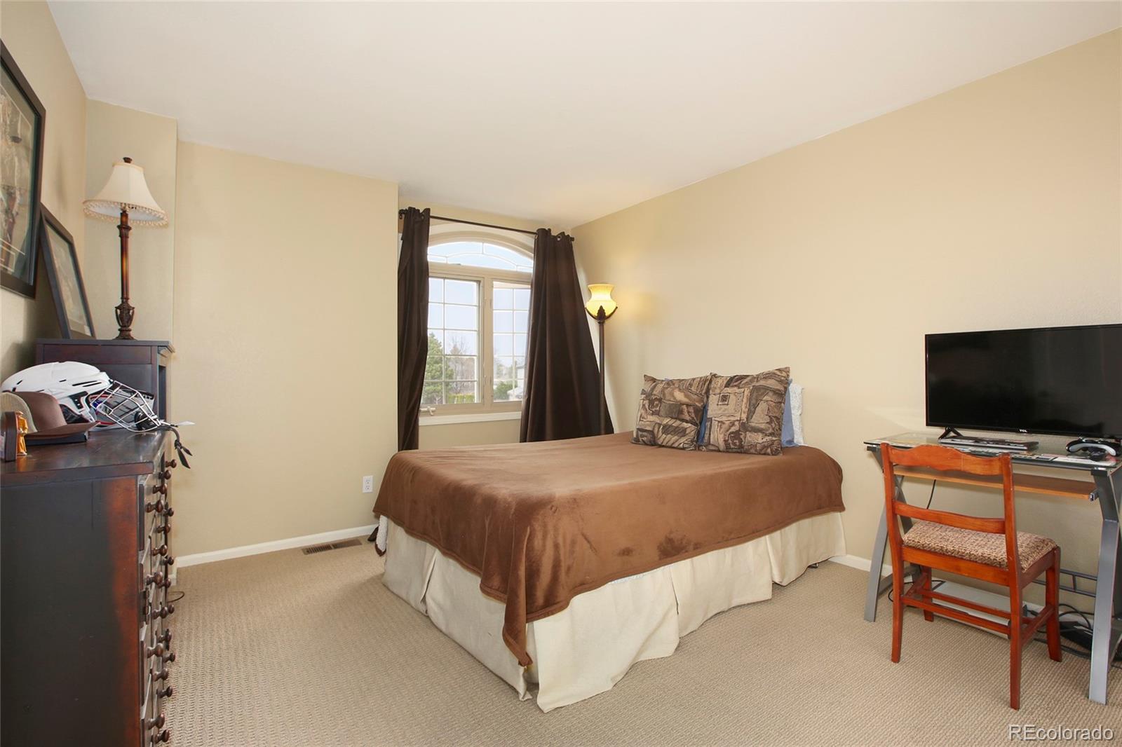 7768 Edgewater Court Lone Tree, CO 80124 - Photo 22 of 39 a bedroom with a bed and a flat screen tv