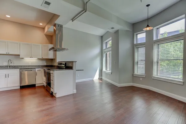 an empty room with wooden floor closet and windows