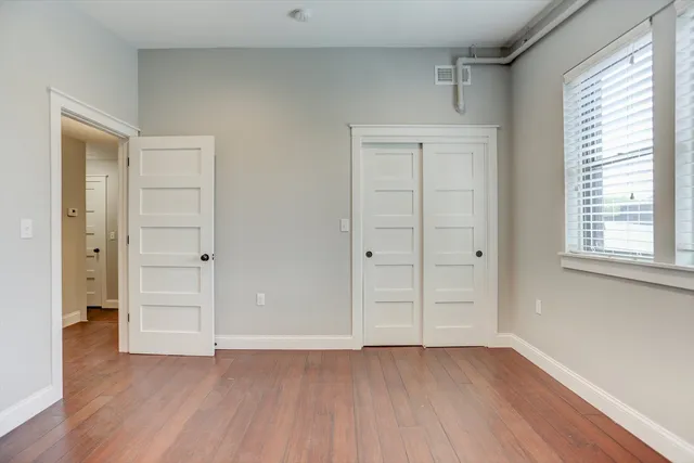 an empty room with wooden floor and windows