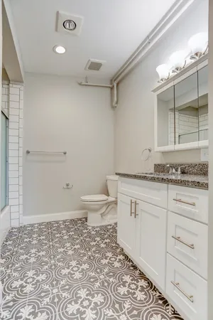 a bathroom with a granite countertop sink a toilet and shower