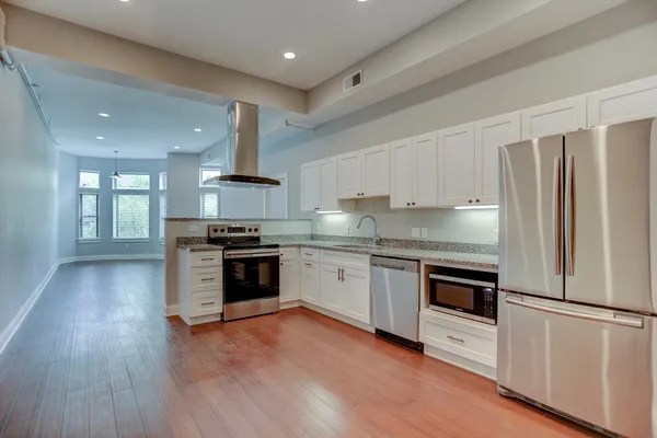 a large kitchen with stainless steel appliances a large counter top a sink a stove and cabinets