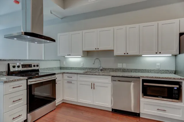a kitchen with stainless steel appliances granite countertop a sink stove and wooden floor