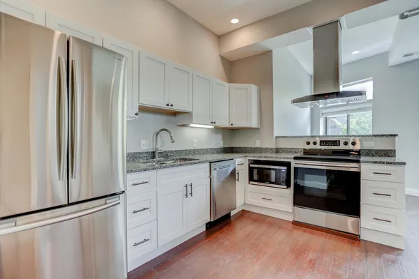a kitchen with stainless steel appliances granite countertop a sink a stove and a wooden floors