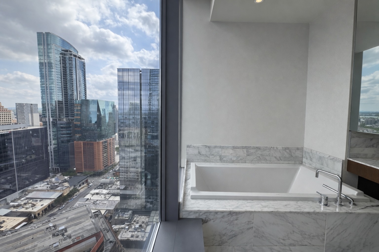 210 Lavaca Street, Unit 2808 Austin, TX 78701 - Photo 15 of 32 The bathroom features a built-in bathtub with a white marble surround and chrome fixtures, complemented by a large window offering expansive city views