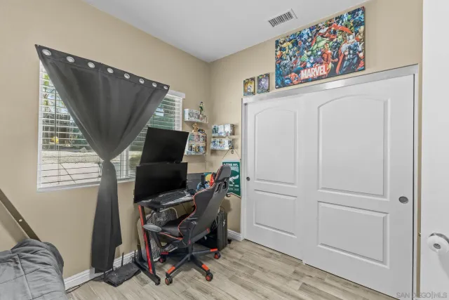 a view of a hallway with wooden floor and a bathroom