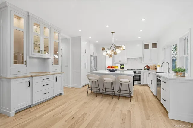 a large kitchen with kitchen island white cabinets and stainless steel appliances
