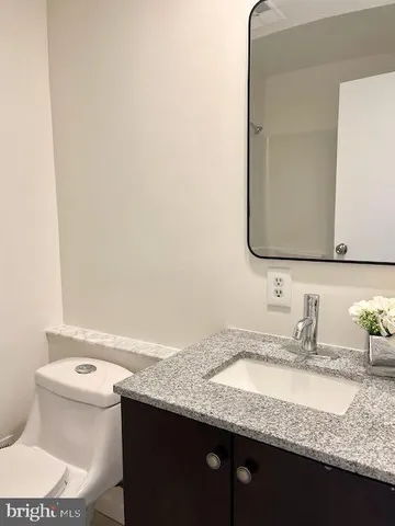 a bathroom with a granite countertop sink and a toilet