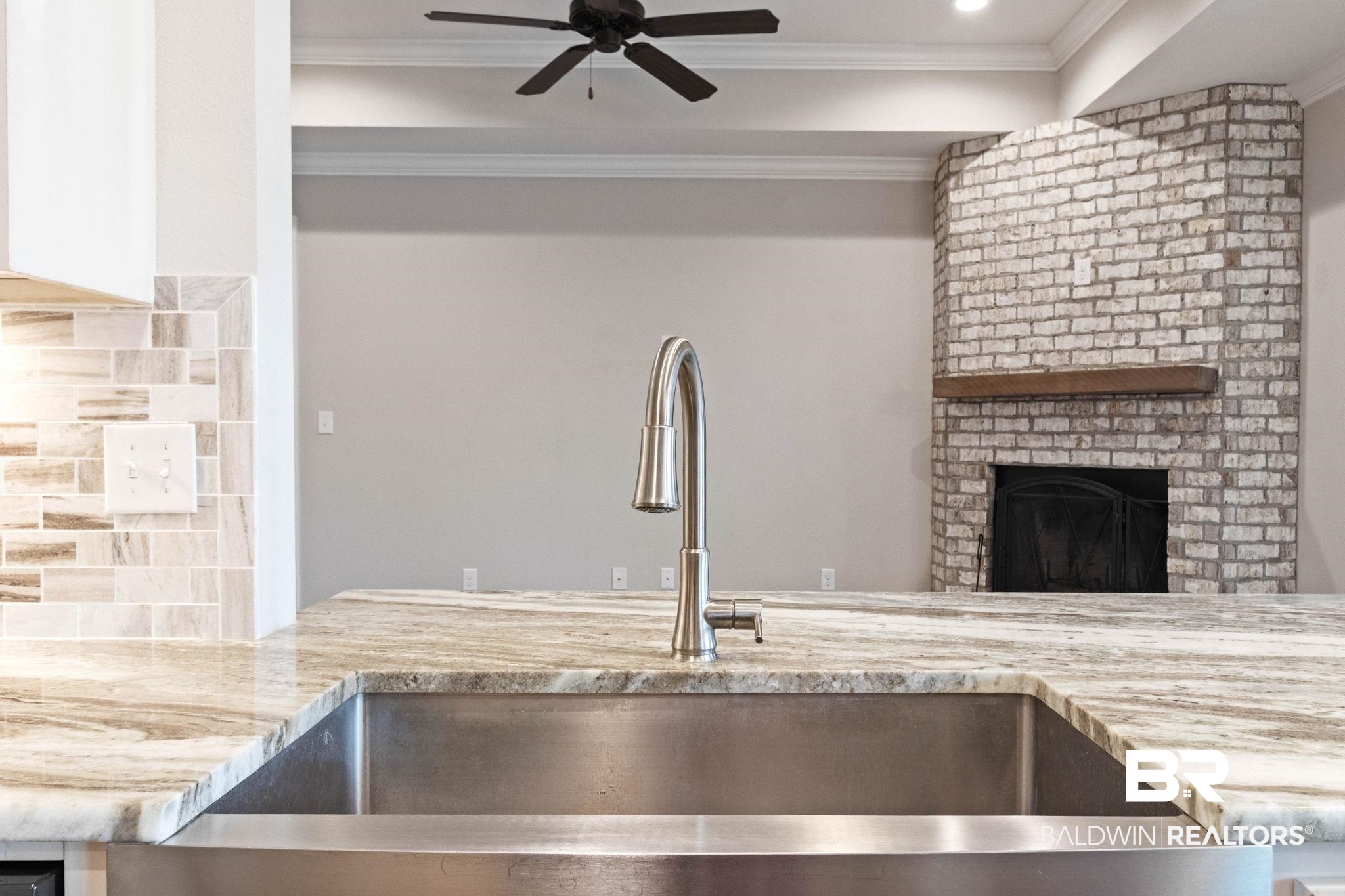 17376 Bankhead Boulevard Fairhope, AL 36532 - Photo 23 of 73 Kitchen featuring backsplash, light stone counters, crown molding, a fireplace, and a ceiling fan