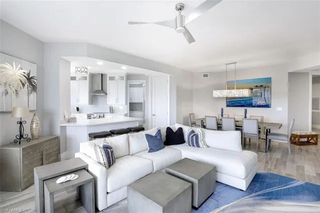 a living room with furniture kitchen view and a wooden floor