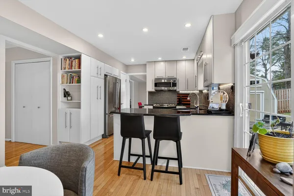 a living room with stainless steel appliances a dining table chairs and a refrigerator