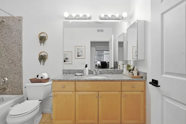 a bathroom with a granite countertop toilet sink and mirror