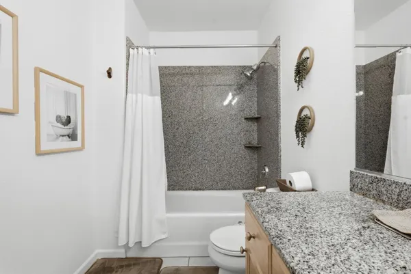 a bathroom with a granite countertop bathtub shower sink and toilet
