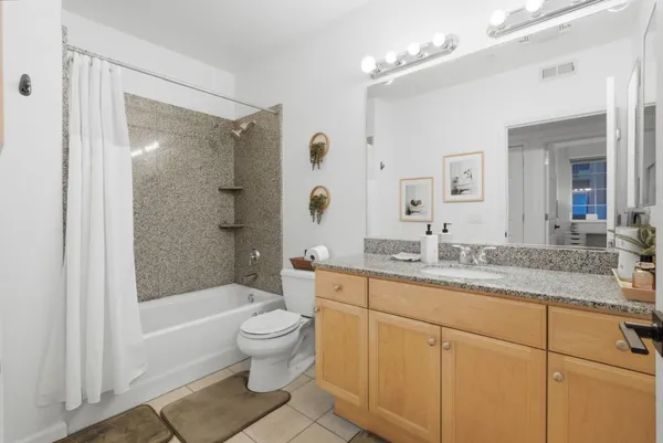 a bathroom with a granite countertop sink a toilet a mirror a bathtub and shower