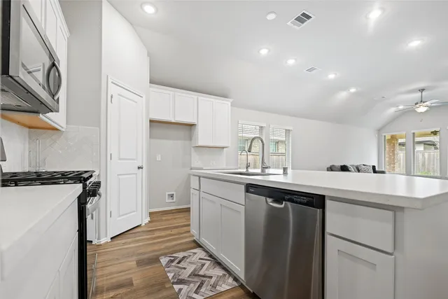 a white kitchen with wooden floor and white appliances