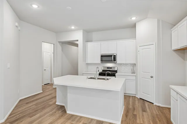 a view of a kitchen with kitchen island a sink wooden floor and a window
