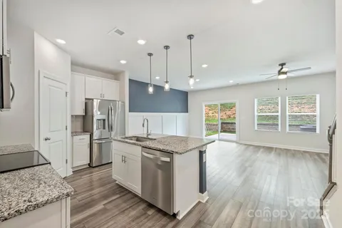 a kitchen with stainless steel appliances granite countertop a stove refrigerator and a sink