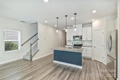 a kitchen with stainless steel appliances kitchen island a refrigerator sink and cabinets