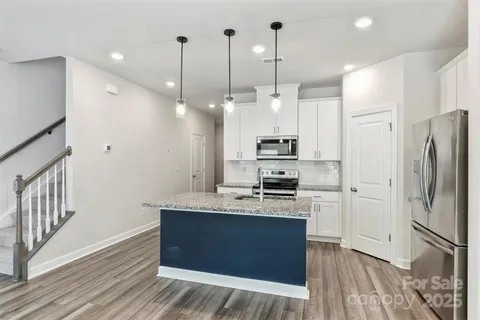 a large kitchen with stainless steel appliances kitchen island granite countertop a refrigerator a stove a sink and a wooden floors