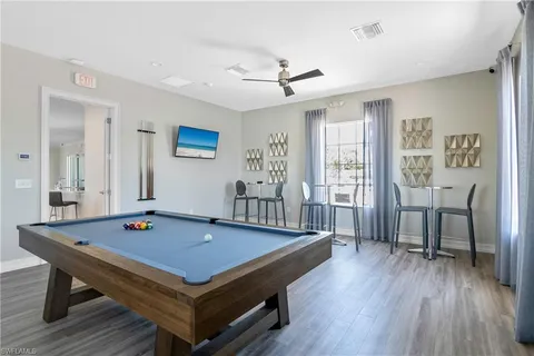 a living room with furniture pool table and wooden floor
