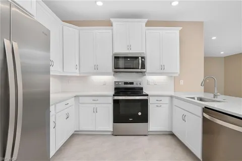a kitchen with white cabinets and stainless steel appliances