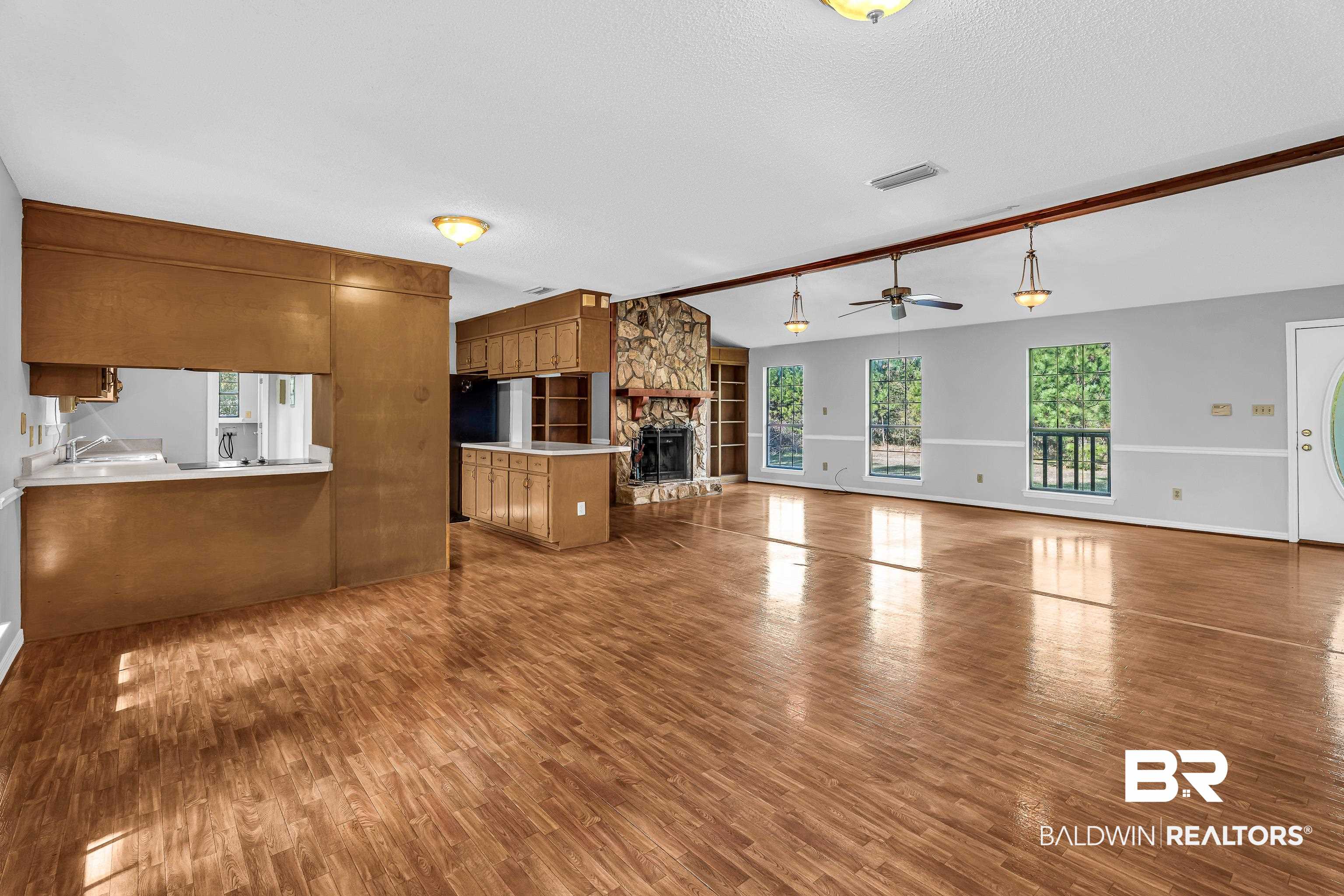 7787 Bellingrath Road Theodore, AL 36582 - Photo 14 of 36 Unfurnished living room with healthy amount of natural light, a stone fireplace, dark wood-type flooring, a ceiling fan, and a textured ceiling